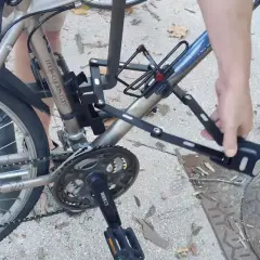 Une main déplie un antivol sur un vélo, prêt pour un vol à vélo électrique.