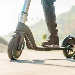Pieds sur une trottinette électrique à vendre, prête pour une balade ensoleillée.