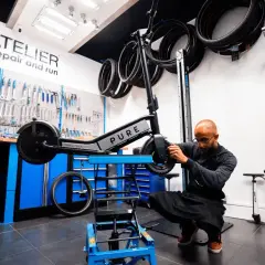 Un mécanicien ajuste une trottinette électrique PURE dans un atelier. Idéal pour ceux qui cherchent à vendre trottinette électrique ou à la faire réparer.