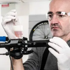 Un mécanicien effectue le purge frein a disque velo, ajoutant du liquide de frein avec une seringue.
