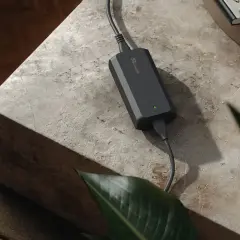 Chargeur 48v noir, compact et discret, posé sur une table en pierre. Une petite plante verte et des livres sont à proximité.