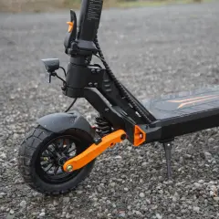 Gros plan sur la roue avant d'une trottinette électrique, dotée d'un pneu 8 pouces tout-terrain et d'une suspension orange vif.