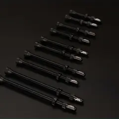 Plusieurs valves Schrader noires, alignées sur un fond sombre, prêtes pour une nouvelle aventure cycliste.