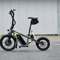 Draisienne électrique pliante grise, prête pour l'aventure urbaine.