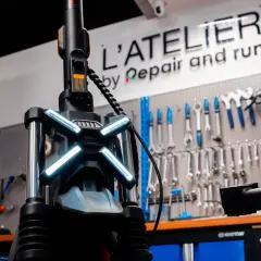 Le guidon d'une trottinette électrique avec ses feux lumineux, prêt pour une réparation à l'atelier.