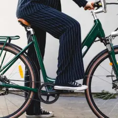Une personne en pantalon à rayures monte un vélo vert, prêt pour une balade fiido.
