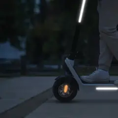 Une trottinette électrique avec une bande réfléchissante sur le guidon et le plateau, pour une visibilité accrue la nuit.