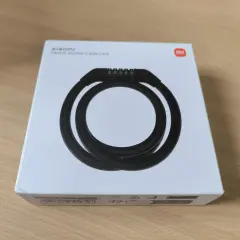 Boîte blanche avec un antivol Xiaomi pour trottinette électrique. Le câble noir est enroulé et un code à 5 chiffres est visible.
