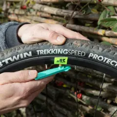 Main d'un cycliste ajustant une chambre à air 700x40c sur une roue de vélo, avec un démonte-pneu vert.