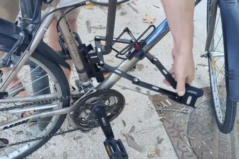 Une main déplie un antivol sur un vélo, prêt pour un vol à vélo électrique.