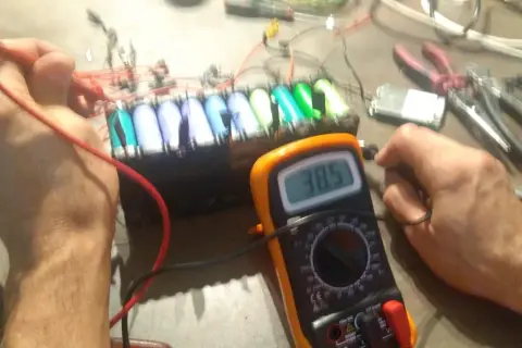 Diagnostic d'un **problème batterie** sur une **draisienne Moovway**. Un multimètre affiche 38.5V, mesurant la tension d'un pack d'accus.