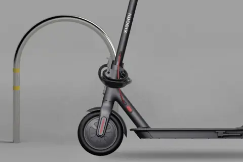 Trottinette électrique Xiaomi sécurisée par un antivol intégré, attachée à un arceau métallique.