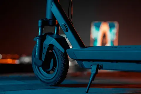 Gros plan sur la roue avant d'une trottinette électrique, prête pour une prise de vue nocturne.