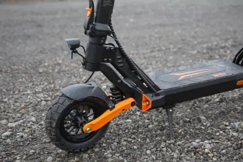 Gros plan sur la roue avant d'une trottinette électrique, dotée d'un pneu 8 pouces tout-terrain et d'une suspension orange vif.