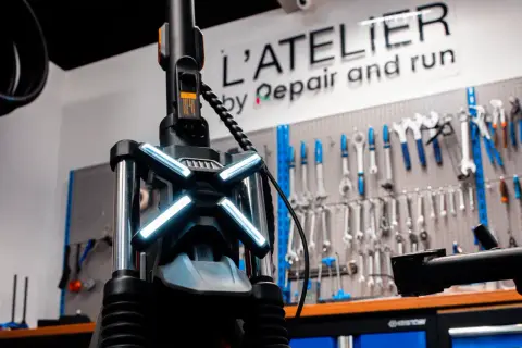 Le guidon d'une trottinette électrique avec ses feux lumineux, prêt pour une réparation à l'atelier.