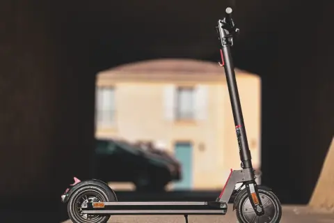 Trottinette électrique Wispeed T850 noire, vue de profil, devant une maison floue.