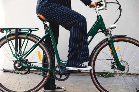 Une personne en pantalon à rayures monte un vélo vert, prêt pour une balade fiido.