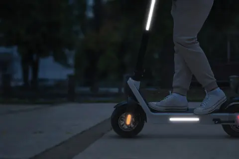 Une trottinette électrique avec une bande réfléchissante sur le guidon et le plateau, pour une visibilité accrue la nuit.