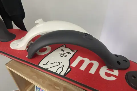 Deux garde boue trottinette Xiaomi, un blanc et un noir, posés sur un deck rouge orné d'un chat.