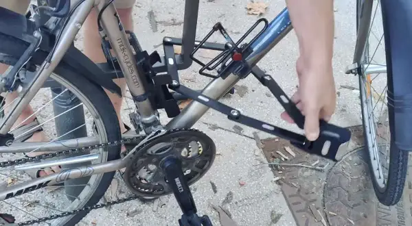 Une main déplie un antivol sur un vélo, prêt pour un vol à vélo électrique.