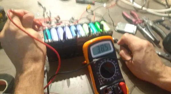 Diagnostic d'un **problème batterie** sur une **draisienne Moovway**. Un multimètre affiche 38.5V, mesurant la tension d'un pack d'accus.