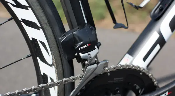 Dérailleur avant SRAM RED, essentiel pour le réglage plateau vélo. La chaîne argentée est visible sur le pédalier noir.