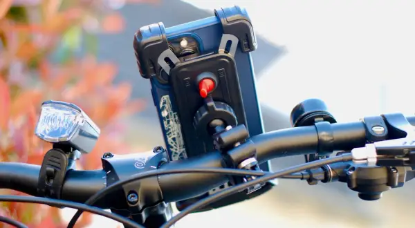 Support téléphone trottinette action : un smartphone est fixé sur le guidon, prêt pour l'aventure.