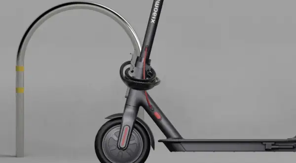 Trottinette électrique Xiaomi sécurisée par un antivol intégré, attachée à un arceau métallique.