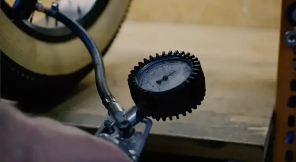 Manomètre mesurant la pression pneu vélo électrique Nakamura. Le pneu est visible, ainsi que le tuyau de la pompe.