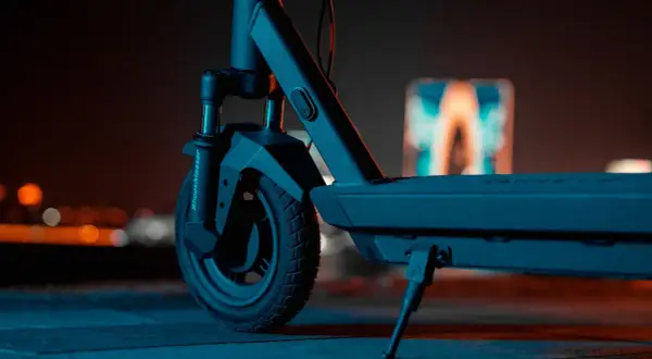 Gros plan sur la roue avant d'une trottinette électrique, prête pour une prise de vue nocturne.