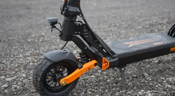 Gros plan sur la roue avant d'une trottinette électrique, dotée d'un pneu 8 pouces tout-terrain et d'une suspension orange vif.