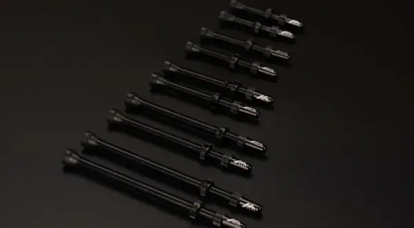 Plusieurs valves Schrader noires, alignées sur un fond sombre, prêtes pour une nouvelle aventure cycliste.