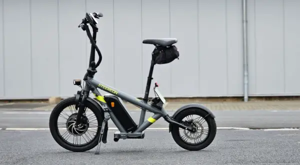 Draisienne électrique pliante grise, prête pour l'aventure urbaine.