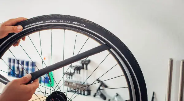 Main d'un cycliste tenant une chambre à air de vélo, prête à être installée. La durée de vie chambre à air vélo dépend de son entretien.