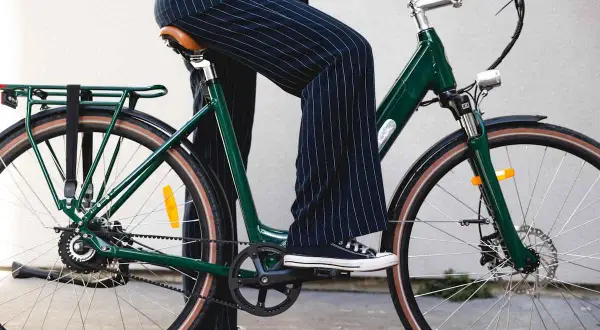 Une personne en pantalon à rayures monte un vélo vert, prêt pour une balade fiido.