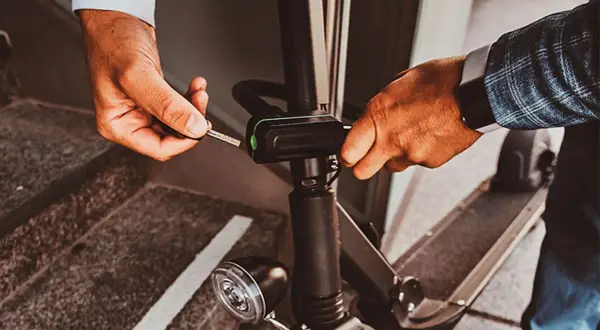 Un homme utilise une clé pour activer l'antivol de sa trottinette électrique, assurant ainsi sa sécurité.