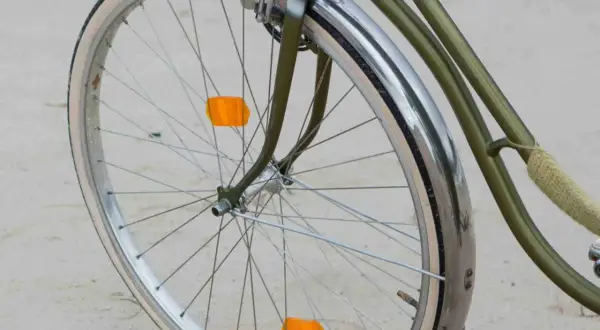 Roue de vélo verte avec garde-boue chromé et deux catadioptres orange pour la sécurité.
