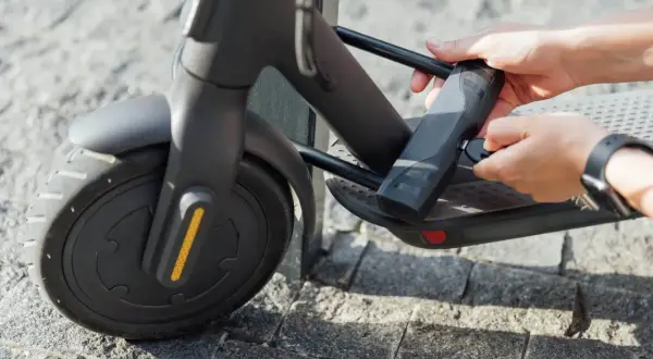 Maintenant, je sais comment cadenasser une trottinette. Des mains insèrent une clé dans un cadenas attaché au cadre de la trottinette.