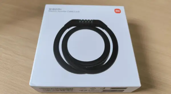 Boîte blanche avec un antivol Xiaomi pour trottinette électrique. Le câble noir est enroulé et un code à 5 chiffres est visible.
