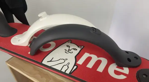 Deux garde boue trottinette Xiaomi, un blanc et un noir, posés sur un deck rouge orné d'un chat.