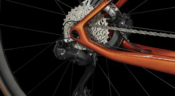 Détail du dérailleur et de la cassette d'un vélo électrique orange. Apprenez comment passer les vitesses sur un vélo électrique pour une conduite optimale.