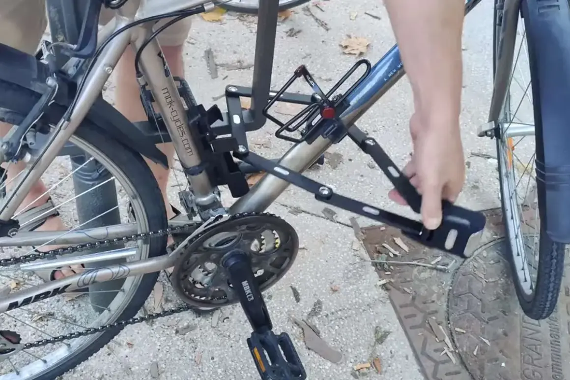 Une main déplie un antivol sur un vélo, prêt pour un vol à vélo électrique.