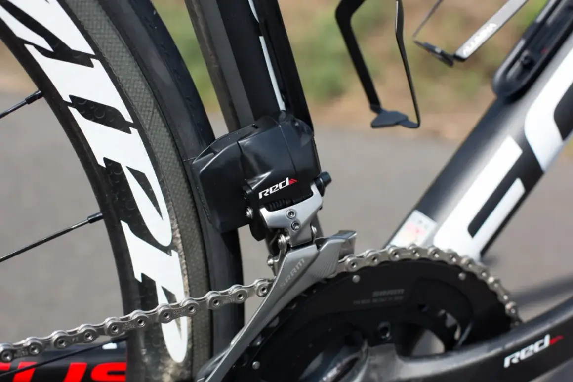 Dérailleur avant SRAM RED, essentiel pour le réglage plateau vélo. La chaîne argentée est visible sur le pédalier noir.