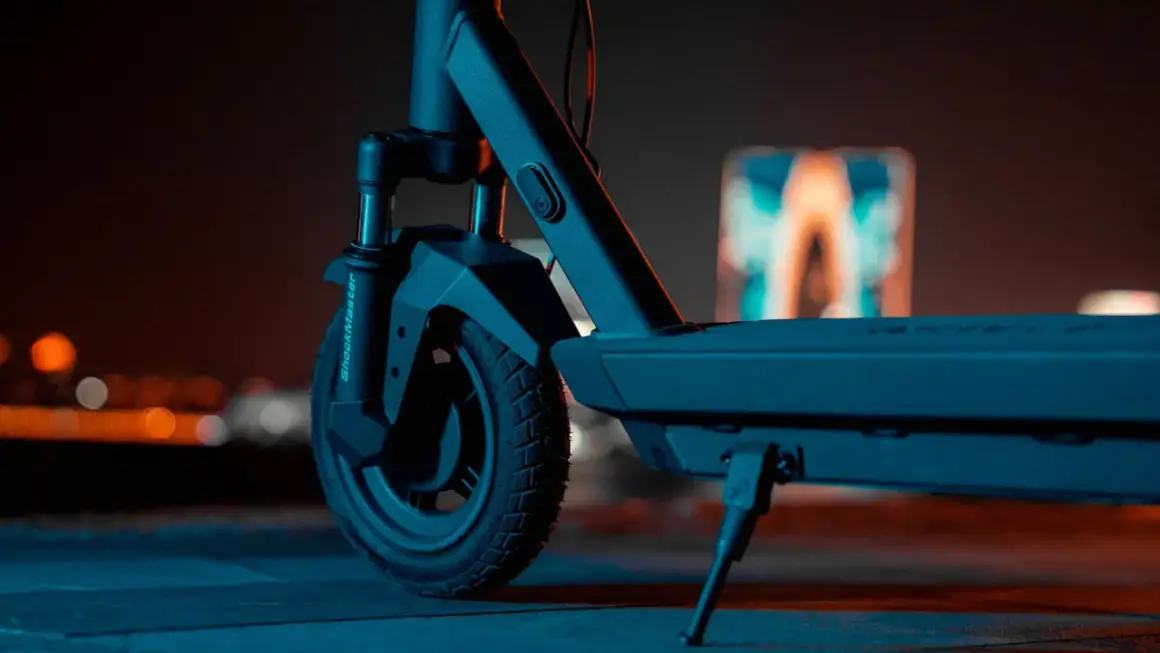 Gros plan sur la roue avant d'une trottinette électrique, prête pour une prise de vue nocturne.