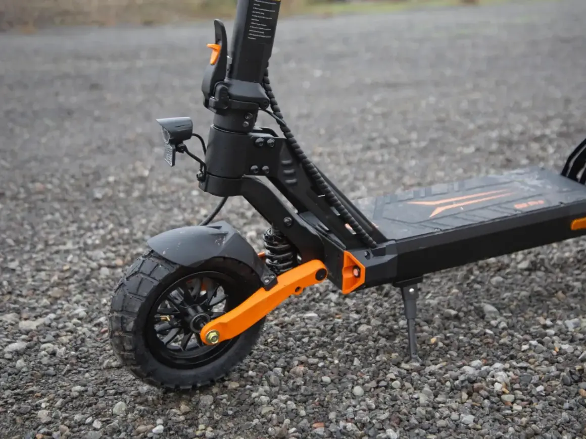 Gros plan sur la roue avant d'une trottinette électrique, dotée d'un pneu 8 pouces tout-terrain et d'une suspension orange vif.