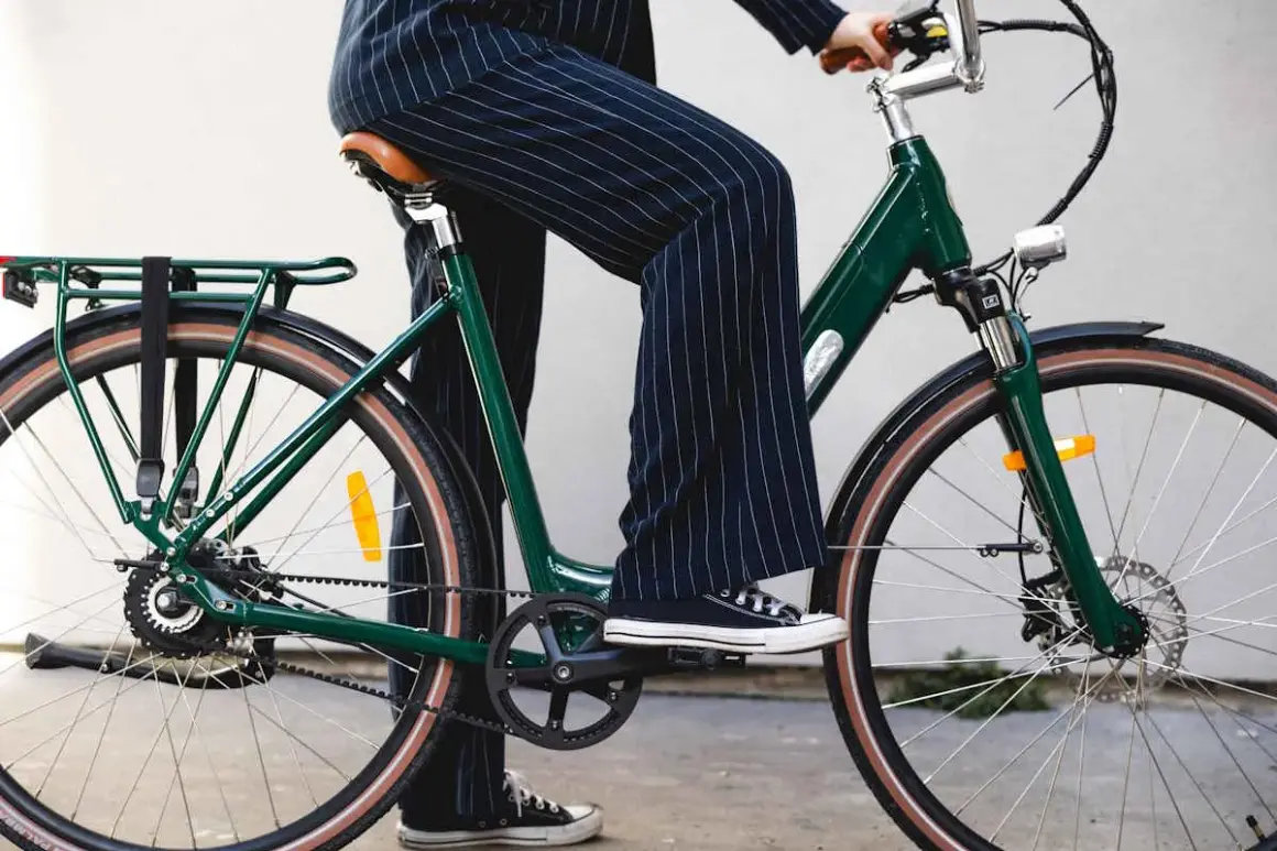 Une personne en pantalon à rayures monte un vélo vert, prêt pour une balade fiido.