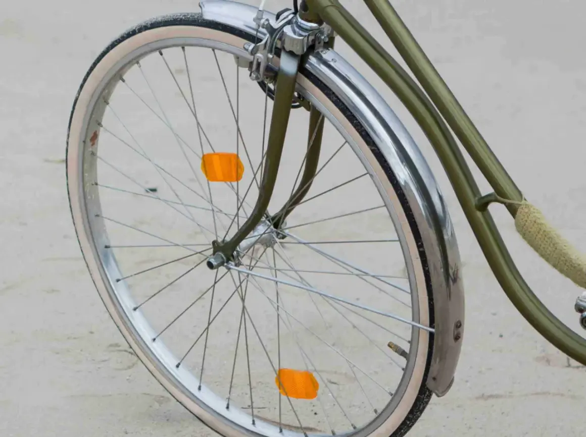 Roue de vélo verte avec garde-boue chromé et deux catadioptres orange pour la sécurité.