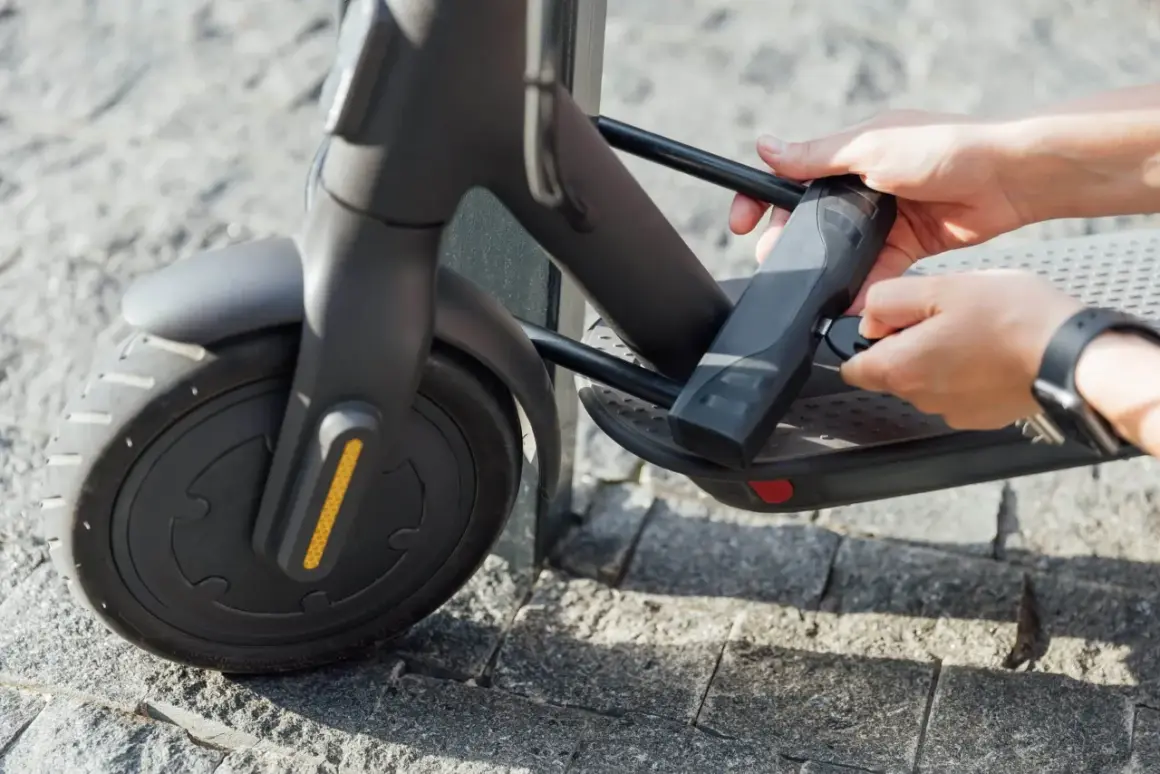 Maintenant, je sais comment cadenasser une trottinette. Des mains insèrent une clé dans un cadenas attaché au cadre de la trottinette.