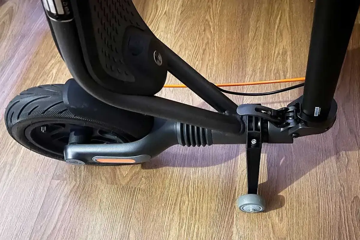 Gros plan sur la roue arrière et le pied d'une trottinette électrique noire, prête pour une balade urbaine.