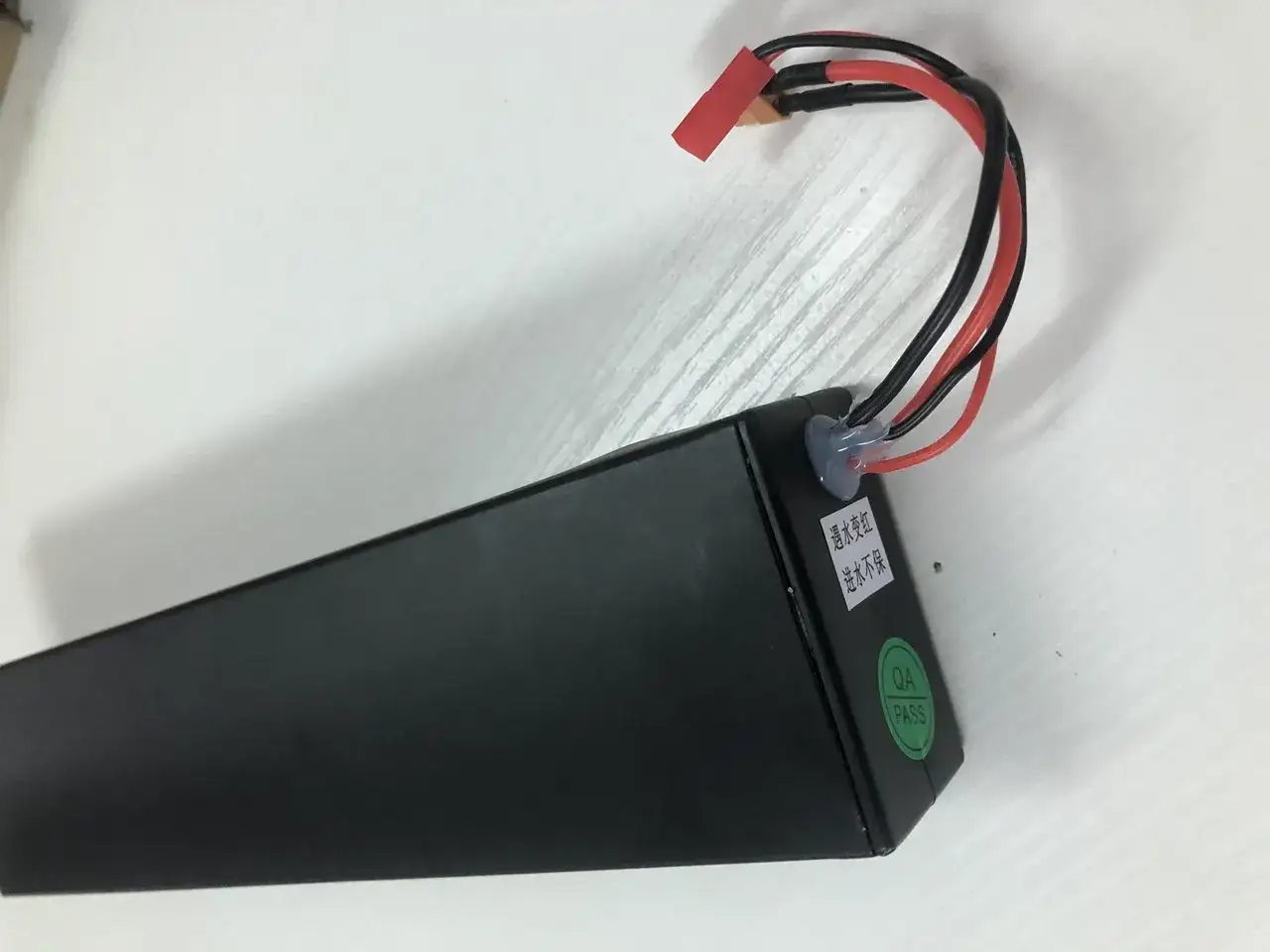 Batterie Aovo Pro noire avec fils rouges et noirs, pr&ecirc;te &agrave; alimenter votre trottinette. Un autocollant 